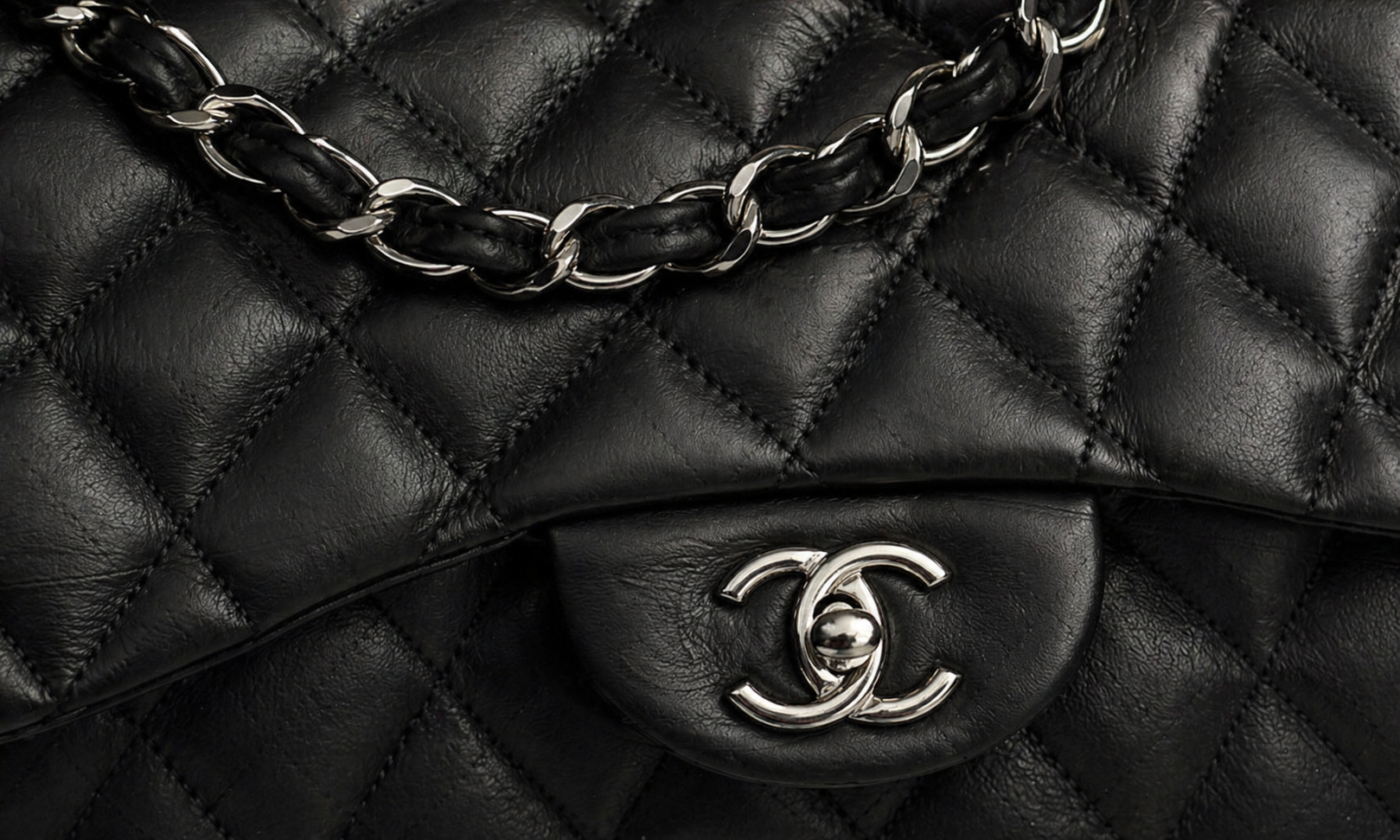 Close-up of a gucci nappa black quilted handbag with a gold chain and logo.